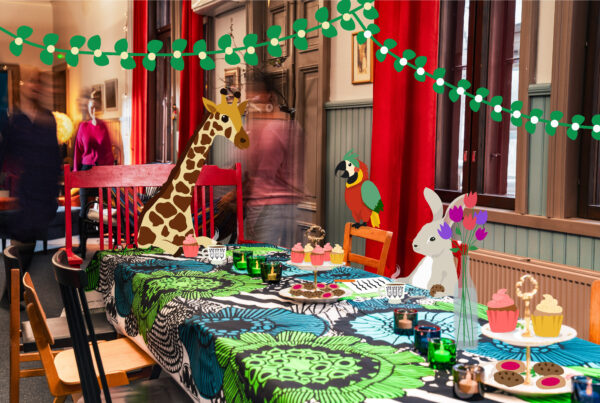 Eläinhahmoja istumassa juhlakahveilla Marimekko pöytäliinalla koristellun pöydän ääressä